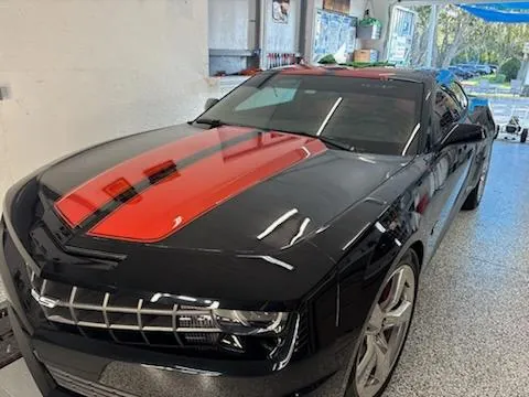 Black Camaro with red stripes after correction and coating